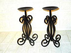 two black metal candlesticks sitting next to each other on top of a table