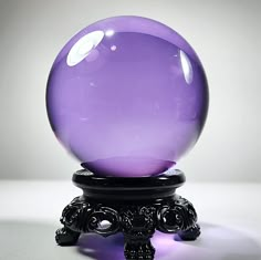 a purple glass ball sitting on top of a black stand