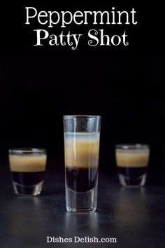 three shot glasses filled with liquid sitting next to each other on a black counter top