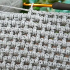 the crochet pattern is being worked on with a knitting needle in front of it