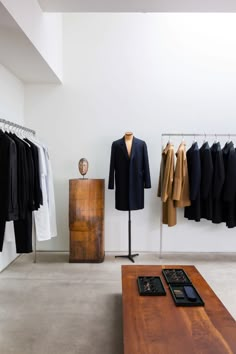 a room with clothes on hangers and a wooden table