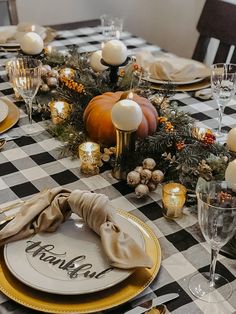 a black and white checkered table cloth with candles, napkins and pumpkins