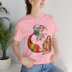 Embrace your inner mermaid with this vibrant "Colorful Mermaid" graphic t-shirt. Made from soft, breathable cotton, this unisex tee offers comfort and style for any casual outing or beach day. *100% Airlume combed and ring-spun cotton for a soft, lightweight feel *Durable print with ribbed knit collars for added shape *Available in various colors and sizes *Ideal for casual wear, beach trips, or as a thoughtful gift *Ethically made by Bella+Canvas Mermaid Graphic, Colorful Mermaid, Mermaid Lover, Beach Trips, Beach Trip, Beach Day, Ribbed Knit, Gender Neutral, Graphic T Shirt