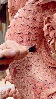 a person is carving a dragon statue with a brush