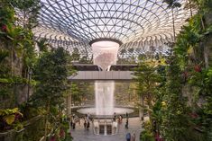 the inside of a building with people walking around and fountains in the center surrounded by greenery