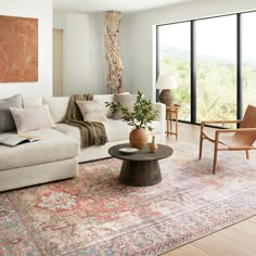 a living room filled with furniture and a large window covered in lots of natural light