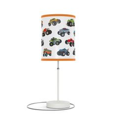 a lamp with monster trucks on it and an orange shade over the top, sitting on a white base