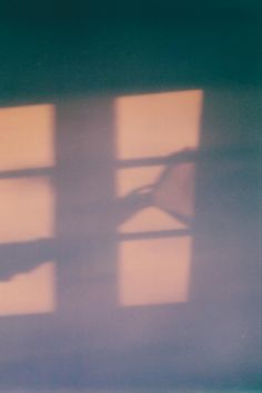 the shadow of a person's hand on a window sill in an empty room