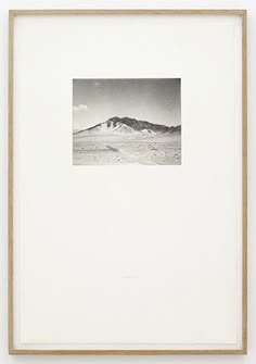 a black and white photo of mountains in the distance with a wooden frame around it