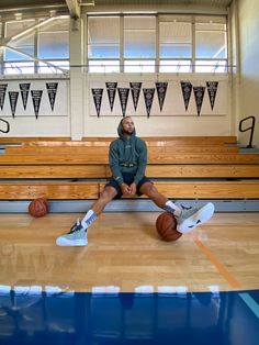 a man sitting on top of a basketball court with his feet up in the air