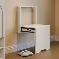 a pair of white shoes sitting on top of a wooden floor next to a shelf