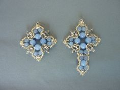 two pairs of blue and gold earrings on a gray surface, one with an intricate design