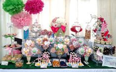 a table topped with lots of different types of candies and desserts covered in paper pom poms