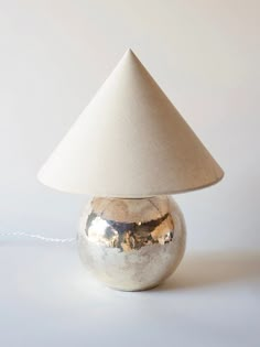 a silver lamp with a white shade on it's top and a cord attached to the base