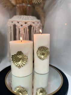 two white candles sitting on top of a plate