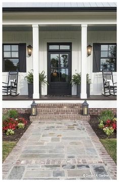 the front porch of a house with rocking chairs and flowers on the steps leading up to it