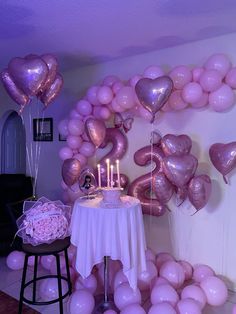 a table topped with pink balloons and a cake