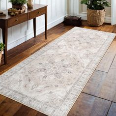 a large rug is sitting on the floor in front of a table with potted plants