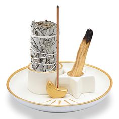 a white plate topped with two cups filled with silver and gold coins next to a wooden stick