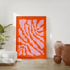 an orange and pink art piece sitting on top of a wooden floor next to two vases