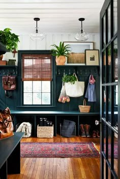 an entryway with green walls and wooden flooring is decorated with hanging planters