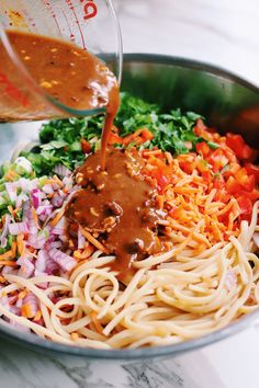 someone is pouring sauce on some noodles in a bowl