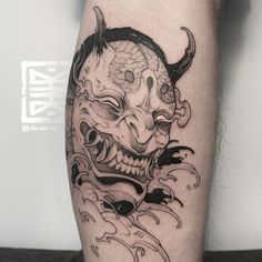 a black and white tattoo on the leg of a man with a demon head in it