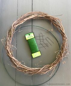 a green spool of thread sits on top of a grapevine wreath