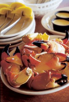 a white plate topped with lots of food on top of a wooden table covered in sauces