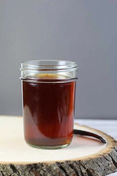 a glass jar filled with liquid sitting on top of a wooden slice