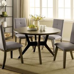 a dining room table with four chairs and a bowl of fruit on top of it