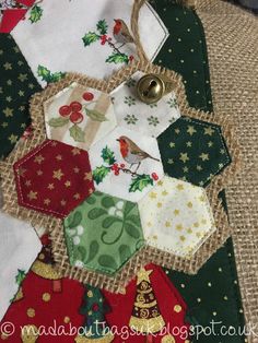 a patchwork christmas ornament hanging on a burlocked piece of fabric