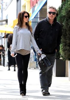 a man and woman walking down the street with one carrying a bag in his hand