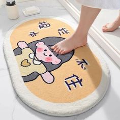 a person standing on top of a bathroom rug with chinese writing and a cartoon bear