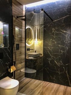 a modern bathroom with black marble walls and flooring, along with a walk in shower