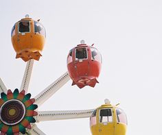 the ferris wheel has four different colored cars on it's front and rear wheels