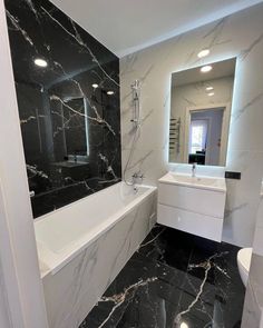 a bathroom with black and white marble flooring next to a bathtub in the corner