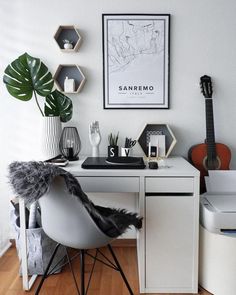 a white desk topped with a laptop computer next to a potted plant on top of a hard wood floor