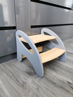 a wooden step stool sitting on top of a hard wood floor next to a gray wall