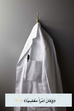 a white jacket hanging on a wall with a black pin in the pocket and an ironing board attached to it