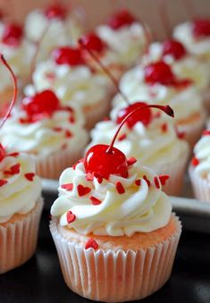 cupcakes with white frosting and cherries on top