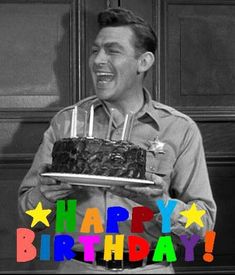 a man holding a birthday cake with candles on it