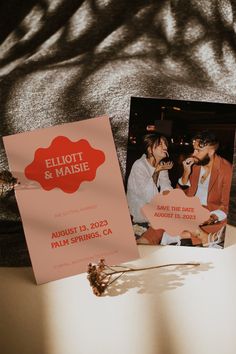 two people sitting next to each other on a table with an orange and pink sign