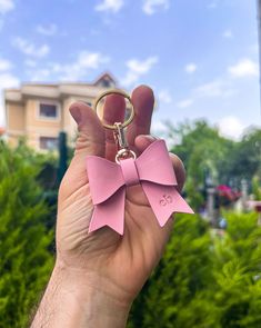 a person holding up a pink bow keychain