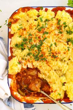 a casserole dish with meat and vegetables in it on a white tablecloth