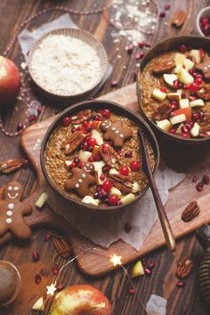 two bowls filled with oatmeal, apples and nuts on top of a wooden cutting board