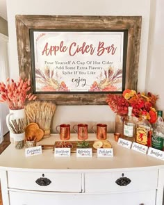 an apple cider bar is set up on a dresser in front of a framed sign