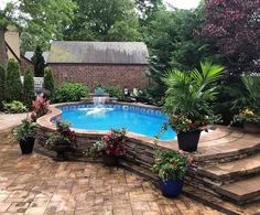 a pool surrounded by plants and flowers in the middle of a patio with steps leading up to it