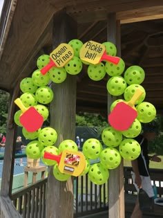 a close up of a wreath made out of green buttons on a wooden pole with people in the background