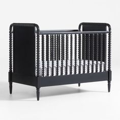 a black and white baby crib with an open side rail on the bottom half